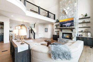 Amplia sala de estar con chimenea, una escalera y un comedor.