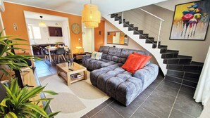 Ein modernes Wohnzimmer mit einem grauen Sofa, einem Holztisch und einer Treppe mit schwarzen Fliesen.