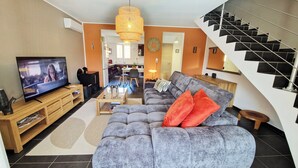 Ein Wohnzimmer mit einer Couch, einem Fernseher, einer Holzunterhaltungseinrichtung und einer Treppe.