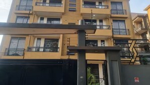 Un immeuble résidentiel à plusieurs étages, doté de balcons, d’une entrée sécurisée et surplombant un ciel dégagé.