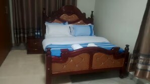 Una cama con cabecera de madera y colcha azul y blanca a rayas.