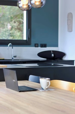 Eine moderne Küche mit einem Laptop auf einem Tisch, einer Kaffeetasse und einem schwarzen Lautsprecher.