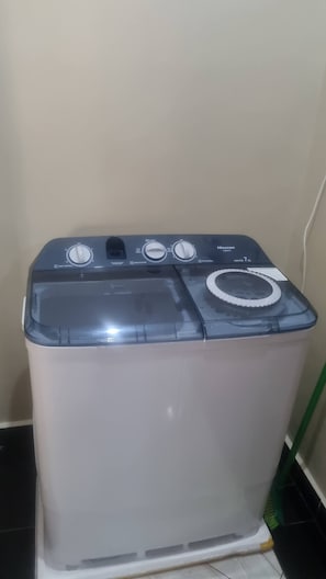 Vista frontal de uma máquina de lavar com botões de controle, porta transparente e etiqueta de capacidade.
