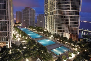 A high-rise building with a rooftop pool area, surrounded by trees and illuminated by night lights. - Modern Brickell Residence for Group Stays (Miami)