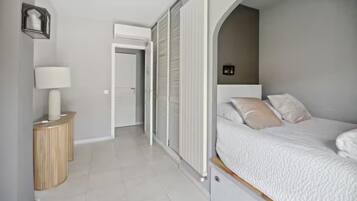 A bedroom with a bed, bedside table, lamp, and a sliding door leading to another room.