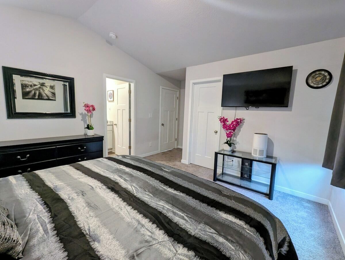 Een slaapkamer met een bed, een televisie, een nachtkastje en een deur naar een andere kamer.