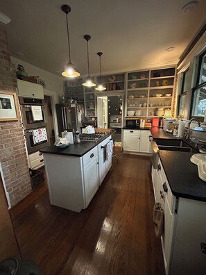 A modern kitchen with a central island, built-in appliances, and pendant lighting. - World Cup rental.  Dallas 3BR historic home 20 minutes to World Cup stadium. (Dallas)