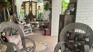Un portico riparato con mobili in vimini, un tappeto decorato e un muro in mattoni.
