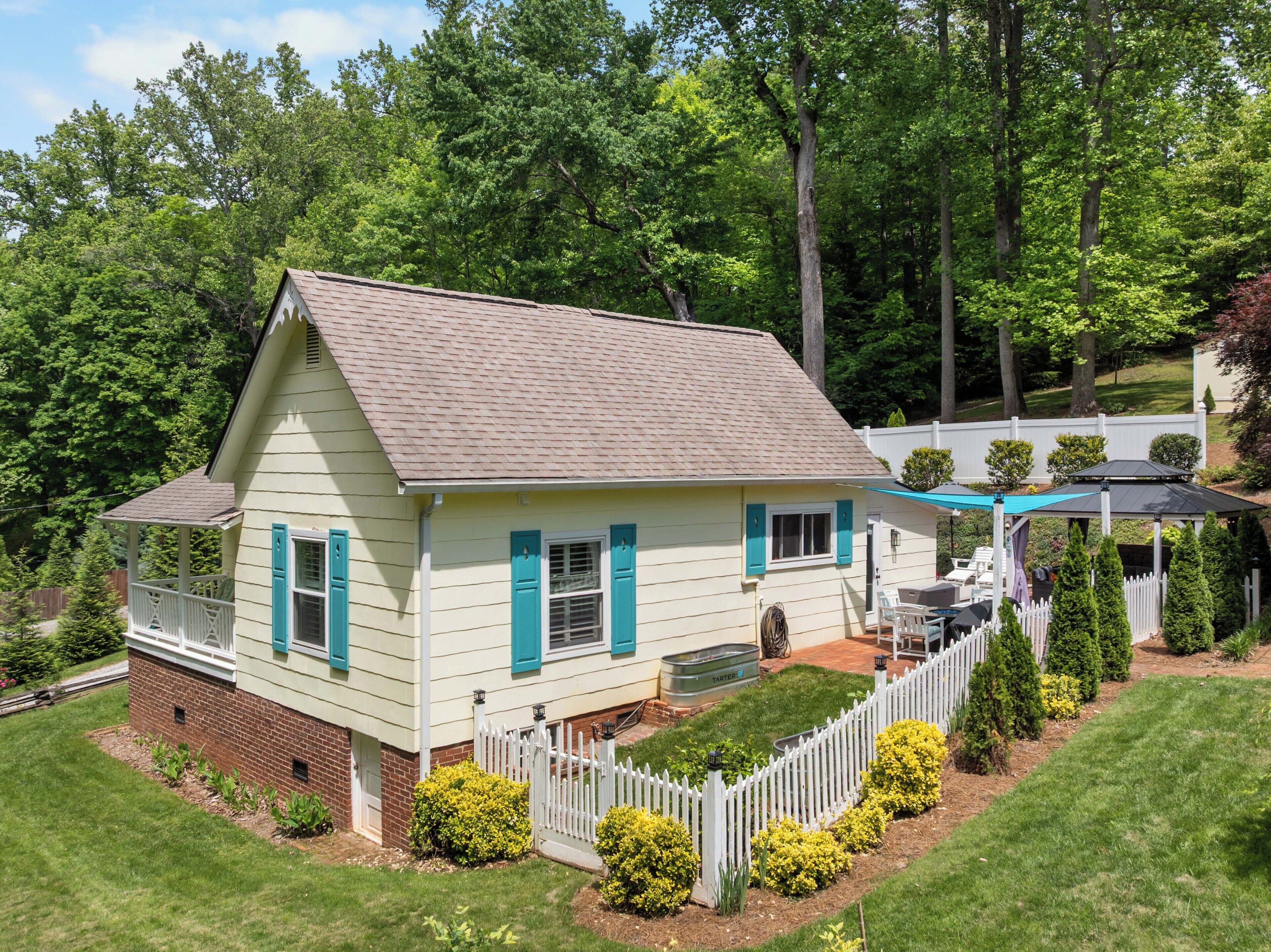 A two-story house with a porch, a fenced yard, and a gazebo.