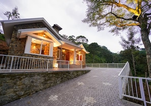 Une maison en pierre avec une allée pavée et une balustrade blanche.