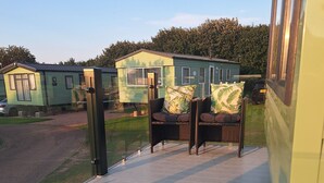 Une terrasse avec des sièges extérieurs et, en arrière-plan, une vue sur des maisons mobiles.