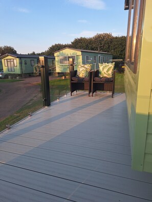 A deck with outdoor seating and a view of mobile homes in the background. - Taigh na Mara, Holiday Home, St Andrews by the Sea (St Andrews)