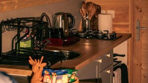 A kitchen with a stove, kettle, coffee maker, and wooden utensils.