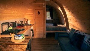 A cozy cabin interior with a kitchen, dining area, and a sleeping loft.