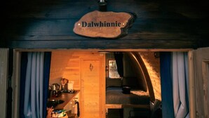A cozy log cabin interior with a visible kitchen area, a fireplace, and a bed.