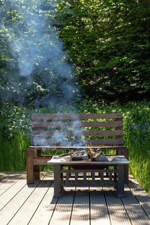 A wooden bench with a fire burning on it, surrounded by greenery. - Green Oak Nature Retreat (Dunfermline)