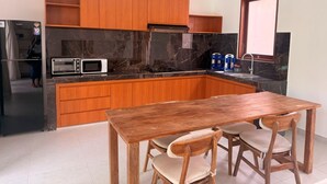 Una cocina con armarios de madera, un microondas integrado y una mesa de comedor con sillas.