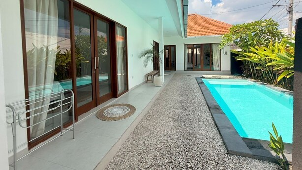 Una casa moderna con piscina, grandes puertas correderas de vidrio y un patio.