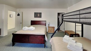 A bedroom with a wooden bed, a bunk bed, a small bedside table, a lamp, and a framed picture on the wall. - Mountain View Cedar Lodge Cabin (Alto)