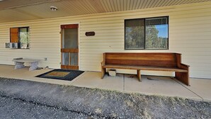 A single-story building with a wooden bench outside, a door, and a window with blinds. - Mountain View Cedar Lodge Cabin (Alto)