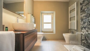 Ein Badezimmer mit großem Spiegel, Waschbecken, Toilette, Bidet und Fenster.