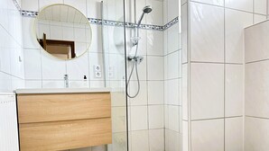 Un baño con tocador de madera, cabina de ducha de vidrio y inodoro.