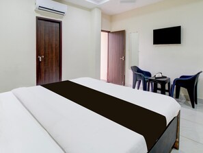 Una habitación de hotel con una cama, un televisor montado en la pared y una pequeña mesa con sillas.