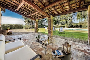 Eine Terrasse im Freien mit einer Pergola, Sitzgelegenheiten, einem Tisch mit Tablett und einer Laterne.