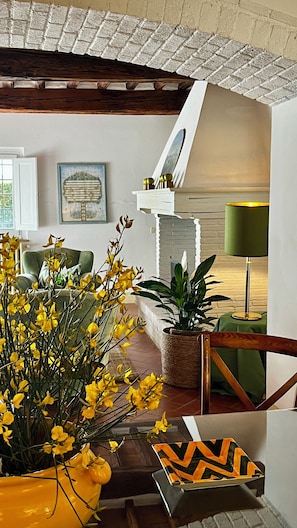 Ein gemütliches Wohnzimmer mit Holzboden, einem grünen Sofa, einem Couchtisch, einer Topfpflanze und einer Lampe.