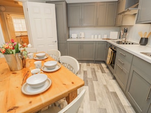 Una cucina moderna con pensili grigi, un tavolo da pranzo in legno apparecchiato con piatti e tazze, e un vaso di tulipani.