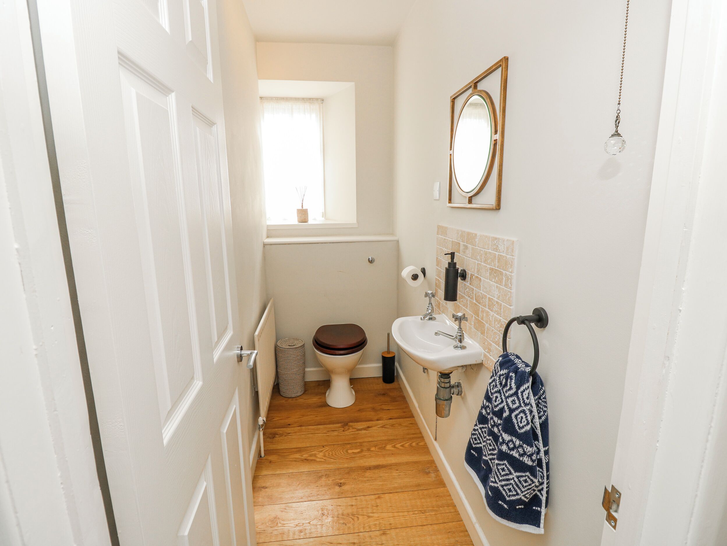 Et lille badeværelse med toilet, håndvask og et vindue.
