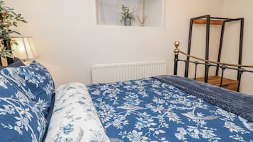 Une chambre à coucher avec un lit, une table de chevet, une lampe, une fenêtre donnant sur un beau paysage et un radiateur.