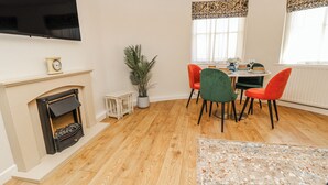A dining area with a fireplace, a flat-screen TV, and a dining table with chairs. - Clifton Lodge (Winchester)
