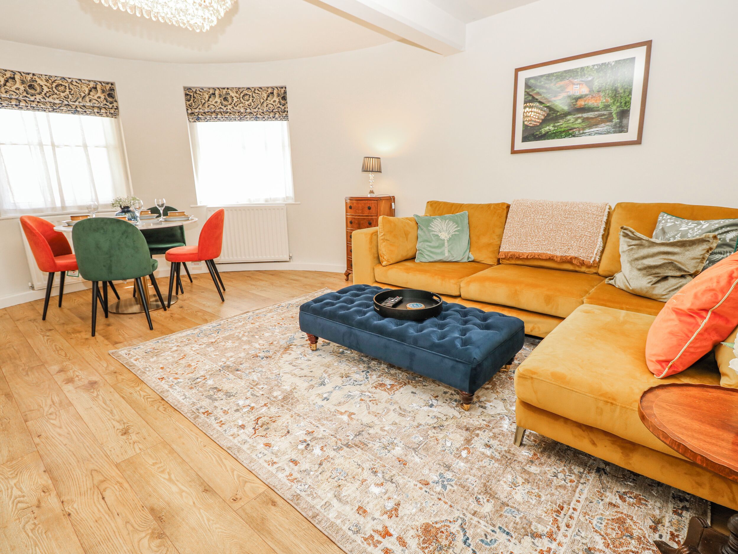 Un salon comprenant un canapé, un pouf, des fauteuils, une table à manger et un tableau accroché au mur.