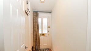 A narrow hallway with a white door, a patterned curtain, and a tiled floor. - Clifton Lodge (Winchester)