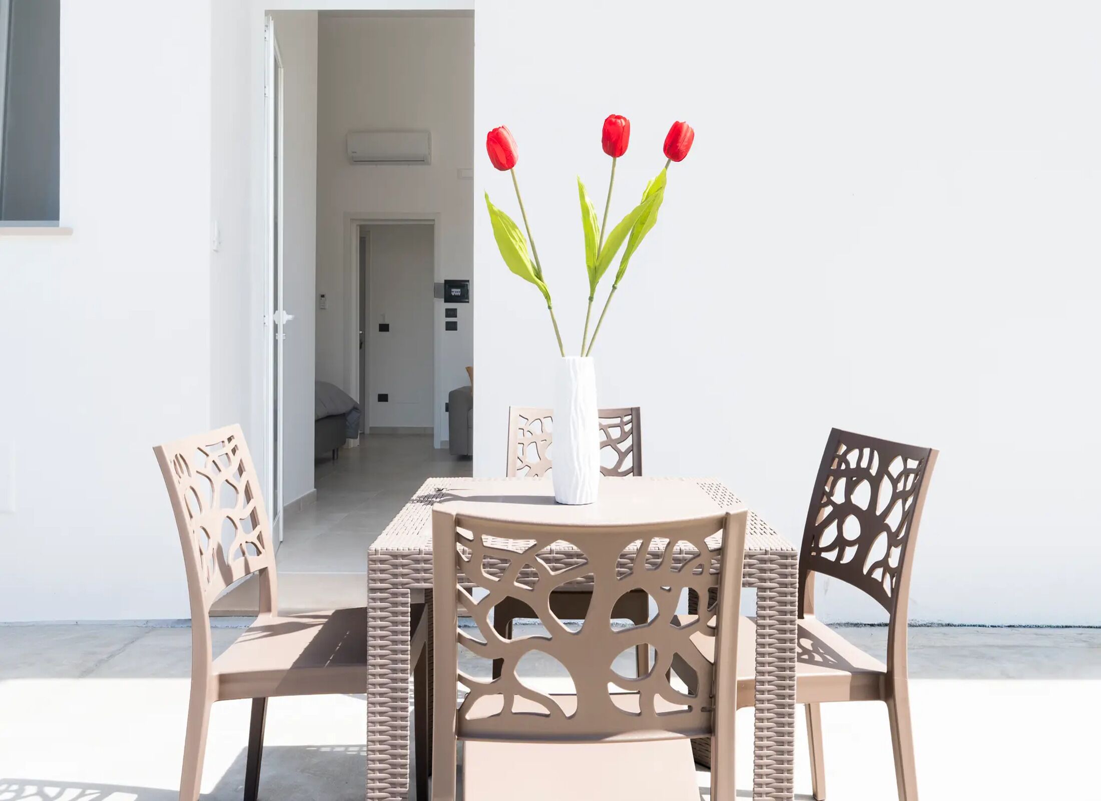 Een tafel met stoelen, een vaas met bloemen en uitzicht op zee.