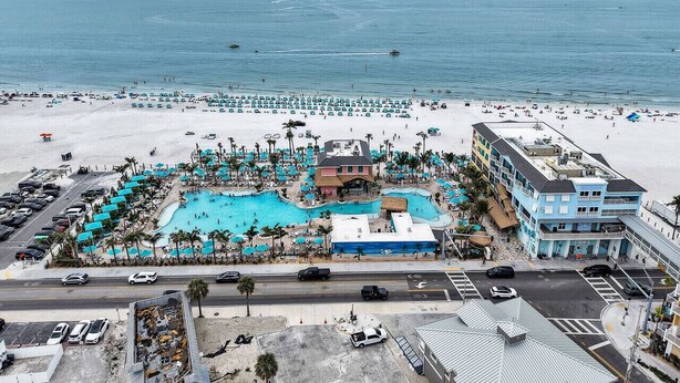 Resort com uma piscina grande, acesso à praia e um edifício com vários andares.