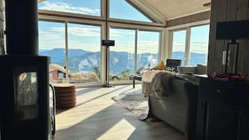 A spacious room with large windows offering a mountain view, a fireplace, and a cozy seating area.