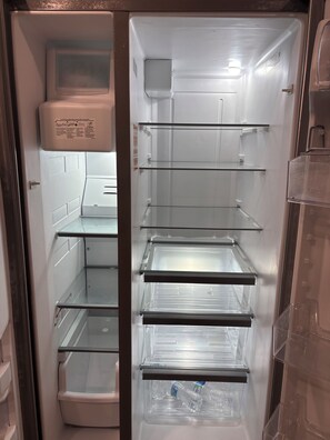 Ein leerer Kühlschrank mit mehreren Ablagen und einem Wasserspender.
