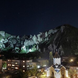 Vista nocturna de un pueblo con una iglesia destacada y edificios con ventanas iluminadas.