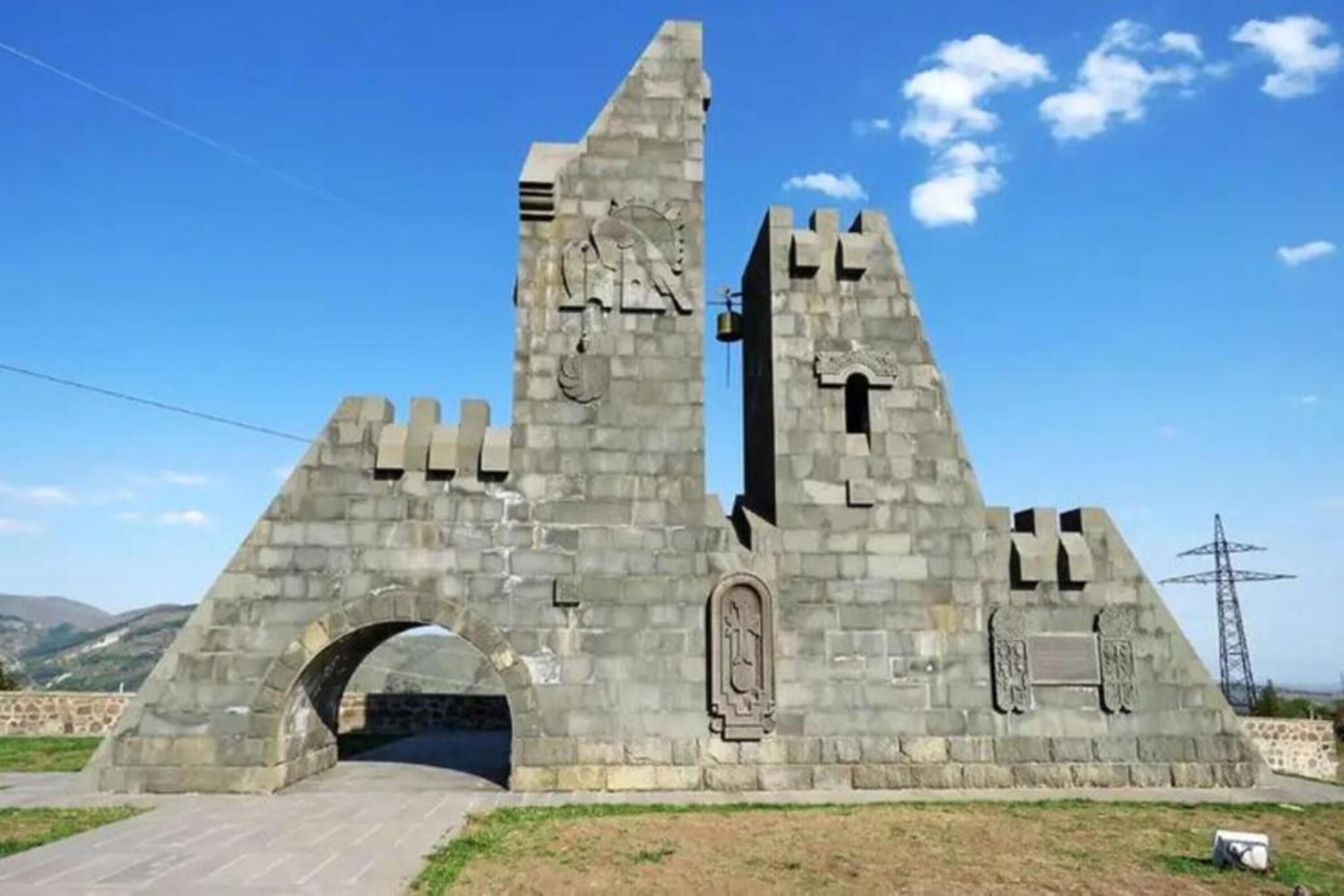 A stone monument with a central archway and two towers, featuring relief sculptures and inscriptions.