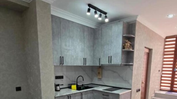 A modern kitchen with grey cabinets, a built-in oven, and a dining area with a table and chairs. - Livana Guesthouse  (Goris)