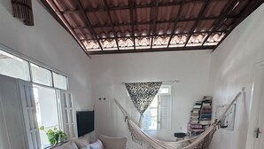 Una sala de estar con sofá, hamaca y televisor.