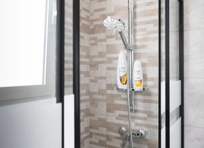 A shower with a rain showerhead, a handheld showerhead, and two bottles of shampoo on a shelf. - Monolocale Vela Nuovo con Wi-fi, Clima e Giardino a Torre Lapillo (Nardò)
