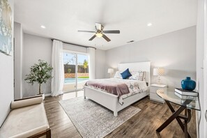 A bedroom with a bed, bedside tables, a glass table, a ceiling fan, and a view of a swimming pool. - Charming 3BR w/ Hills Views, Pool & Billiards (Hemet)