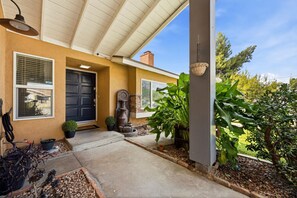 A house with a covered porch, a black door, and a window with blinds. - Charming 3BR w/ Hills Views, Pool & Billiards (Hemet)