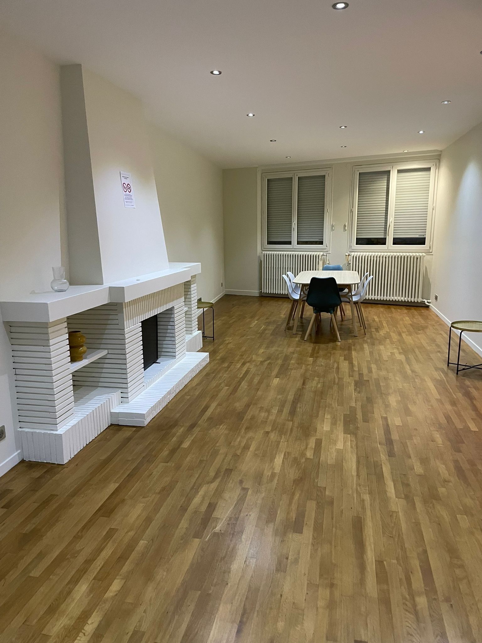 A room with a fireplace, a dining table with chairs, and a radiator.