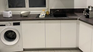 Una cocina moderna con lavadora, un lavamanos y una ventana con persianas.