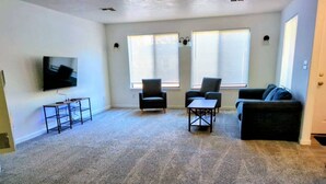 A living room with a TV, two armchairs, a sofa, and a small table. - Cozy GP Retreat, Sauna + King Size Bed (Grants Pass)