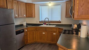 A kitchen with wooden cabinets, a stainless steel refrigerator, a sink, and a stove. - Cozy GP Retreat, Sauna + King Size Bed (Grants Pass)